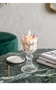 Detail eines brennenden Tulpen-Glaskerzenhalters mit Goldflocken und roten Blüten.