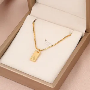 Primer plano detallado de un colgante cuadrado dorado con la letra A grabada en cadena box