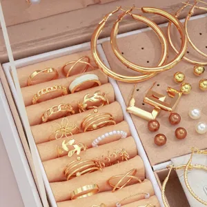 Nahaufnahme eines goldenen Schmucksets aus Legierung mit Perlenringen und Creolen