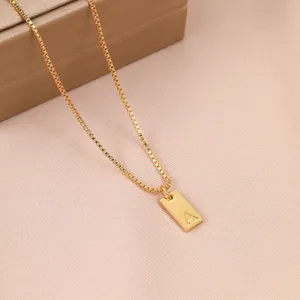 Vista macro detallada de un collar de oro con un colgante rectangular grabado con la letra A