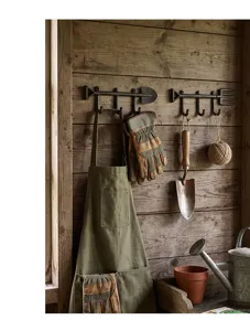 Rustikale Wandhaken aus Gusseisen in Schaufel- und Rechenform an einer Holzwand