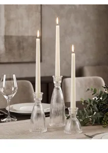 Primo piano di tre candelabri in vetro a coste con candele accese su un tavolo da pranzo
