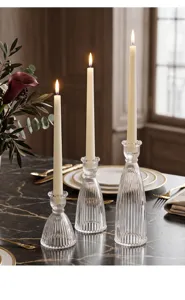 Set di tre eleganti candelabri in cristallo nervato su un tavolo di marmo scuro