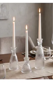 Dettaglio di candelieri in vetro a coste su una tavola da pranzo ben decorata.