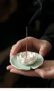 Dettaglio di un porta incenso a forma di loto in ceramica con un fumo elegante.