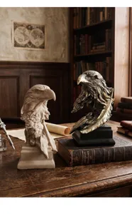 Detalle de dos estatuas de cabeza de águila de resina en gris y bronce en un escritorio vintage