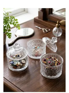 Vintage embossed clear glass storage jars with lids shown on a rustic wooden dresser top