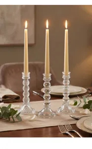 Tres elegantes candelabros de cristal transparente en una mesa romántica puesta.