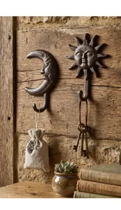 Gros plan de crochets muraux rustiques en fonte soleil et lune montrant la texture