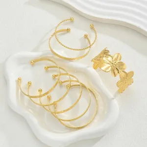 Detailed view of an 8-piece gold-toned bracelet set featuring a floral cuff on a white tray