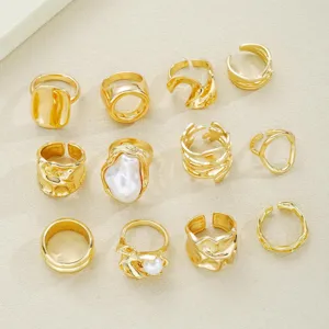 Vista detallada de un conjunto de 12 anillos bañados en oro con perlas y diseños irregulares