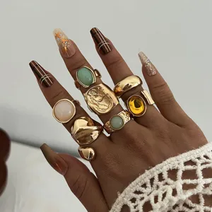 Primer plano de un conjunto de anillos de oro vintage bohemios con piedras en la mano.
