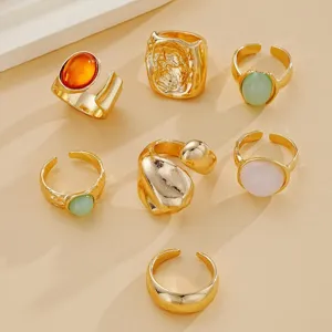 Detalle de siete anillos bohemios dorados vintage con piedras de resina de colores.