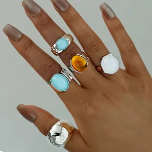 Elegante juego de anillos bohemios vintage con piedras turquesas y ámbar en la mano