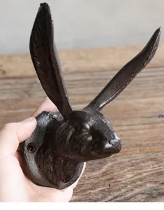 Detail van een rustieke gietijzeren konijnenkop wandhaak in de hand voor decoratie