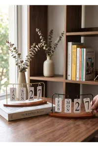 Calendrier perpétuel rétro en fer sur une table en bois avec des livres.