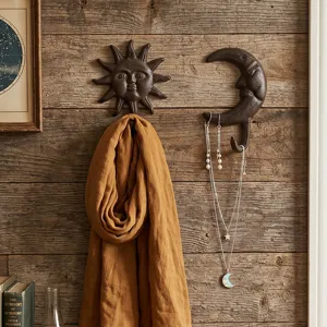 Crochets muraux décoratifs vintage en fonte soleil et lune sur un mur en bois rustique