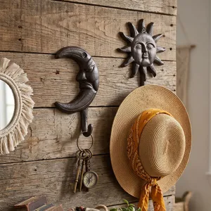 Crochets muraux décoratifs en fonte soleil et lune sur un mur en bois rustique