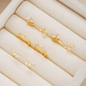Close-up detail of a gold-plated zircon earring set inside a beige velvet jewelry box