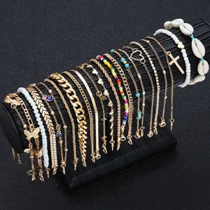 Detailed view of 22pcs gold anklet set with cross, shell, and colorful beads on display