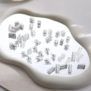 Detailed shot of 50pcs silver hollow hair cuffs for dreadlocks on a mirror surface