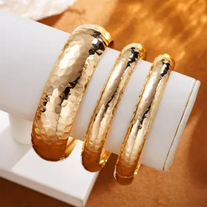 Gros plan sur d'élégants bracelets rétro en métal doré avec une finition martelée texturée