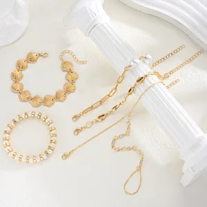 Colección de pulseras doradas con conchas y perlas y detalle de cadena para el dorso.