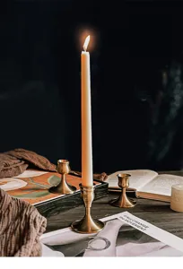 Lifestyle view of vintage brass aluminum candle holders on a dark rustic table
