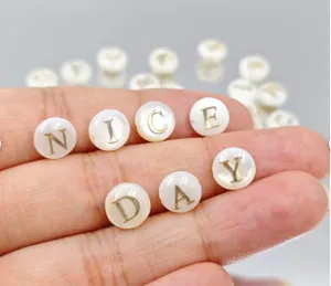 Nahaufnahme von natürlichen Perlmuttperlen mit goldgeprägten Buchstaben für DIY Schmuck.