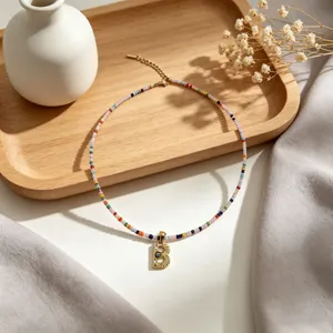 Squisita collana di perle in stile bohémien con dettaglio pendente lettera oro 18k.