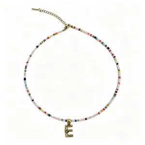 Dettaglio in primo piano della collana di perline colorate con ciondolo lettera E.