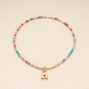 Vue détaillée du collier de perles colorées avec pendentif lettre A doré pour femmes.