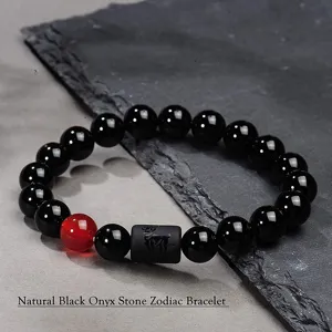 Primer plano detalle de pulsera zodiaco de piedra onix negro natural con cuenta roja.