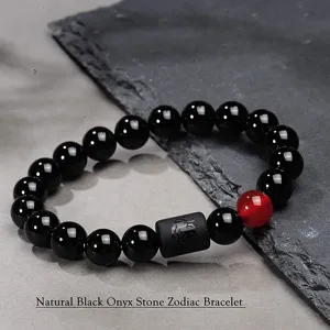 Primer plano detallado del pulsera zodiacal con cuentas de ónix negro y cilindro grabado.