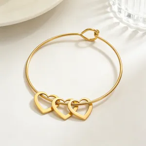 Detailaufnahme des goldenen Edelstahl-Armreifs mit drei wunderschönen hohlen Herz-Anhängern.