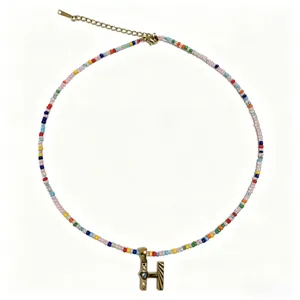 Collana bohémien con perline colorate e ciondolo con lettera H dorata alla moda.