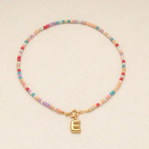 Collier de perles bohème coloré avec un pendentif lettre E doré chic. Vue détaillée.