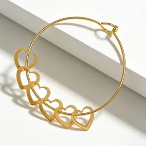 Goldfarbenes Edelstahloffenarmband mit mehreren filigranen hohlen Herz-Anhängern Detail.