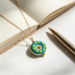 Nahaufnahme einer süßen Emaille Donut Anhänger Halskette mit blauen und gelben Punkten weißer Tisch.