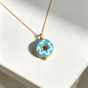 Nahaufnahme des süßen blauen Emaillierter-Donut-Anhängers auf einer sauberen weißen Fläche.