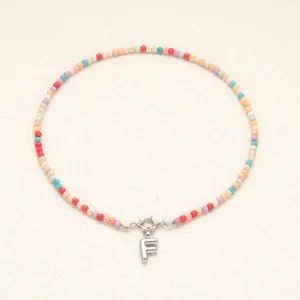 Vue détaillée du collier de perles colorées avec pendentif lettre F argenté et fermoir.
