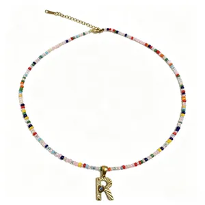 Elegante collana di perle colorate con ciondolo lettera R dorata e catenella.