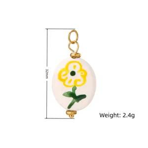 Colgante ovalado de cerámica con flor dorada, anillo de oro, accesorio de joyería detalle.