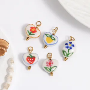 Primer plano detallado de dijes de cerámica pintados a mano de flores y fresas para joyería.