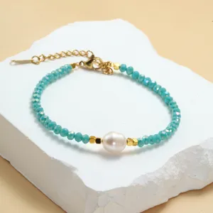 Detailopname van een turquoise kristallen kralenarmband met een centrale zoetwaterparel en goud.