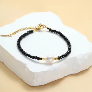 Gedetailleerde close-up van zwarte kristalen kralenarmband met zoetwaterparel en goudkleurige ketting.