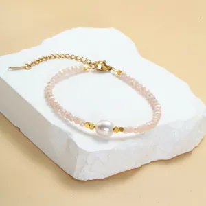 Detailopname van een roze kristallen kralenarmband met een witte parel in het midden.