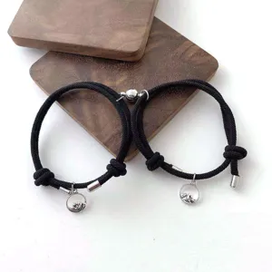 Gros plan de bracelets de corde tressée noire magnétique de couple avec des pendentifs montagne.