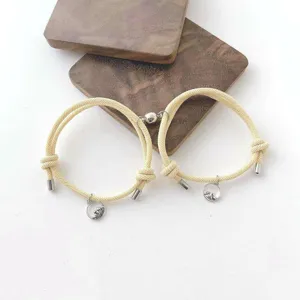 Gros plan de bracelets de couple magnétiques assortis avec breloques montagne et vague sur beige.