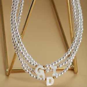 Collier ras du cou multi-couches en fausses perles avec pendentifs lettres en coquillage.